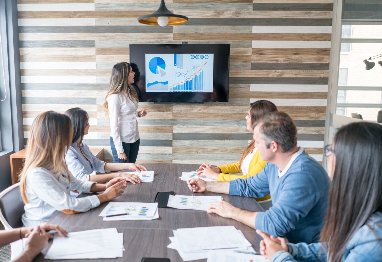 A woman presenting the event data to a marketing and sales team. 